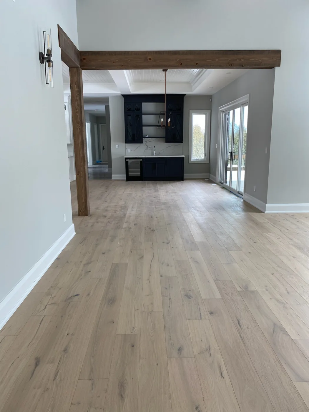Wood plank flooring extending through adjoining rooms framed by wood beams.