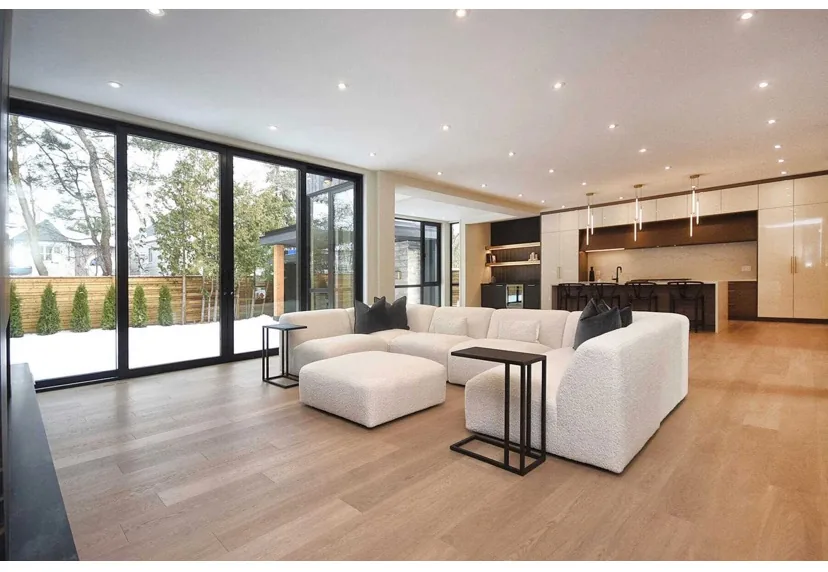 Light plank flooring in an open living room with floor-to-ceiling windows.