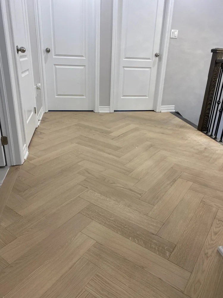 Herringbone wood flooring with a straight border beside white interior doors.