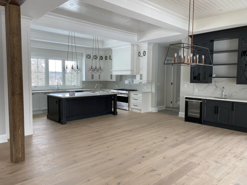 Wood plank flooring through a kitchen and dining space with exposed wood beams.