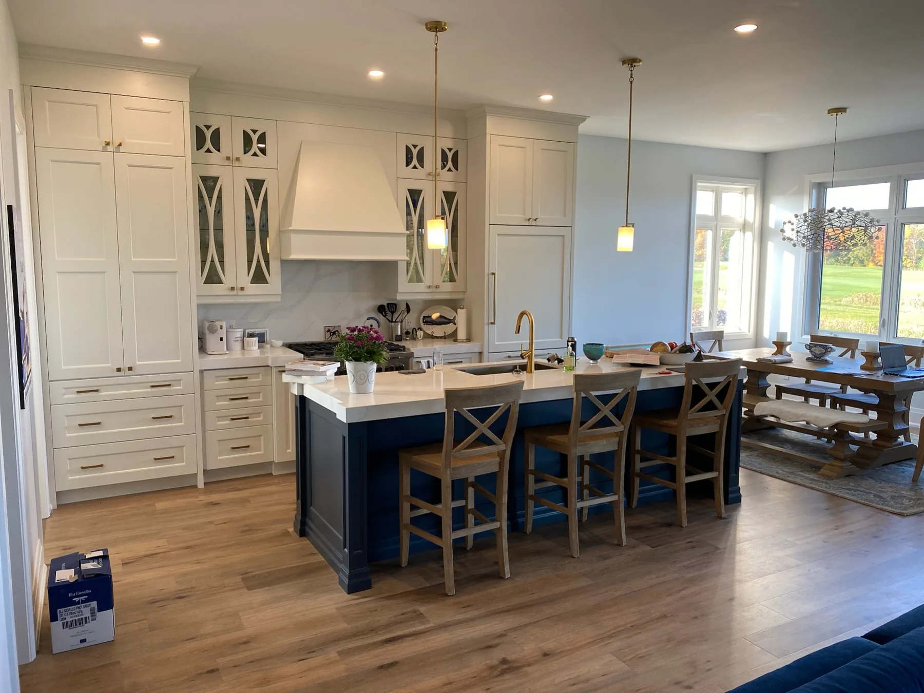 Natural wood flooring in a bright kitchen with white cabinets and a navy island.