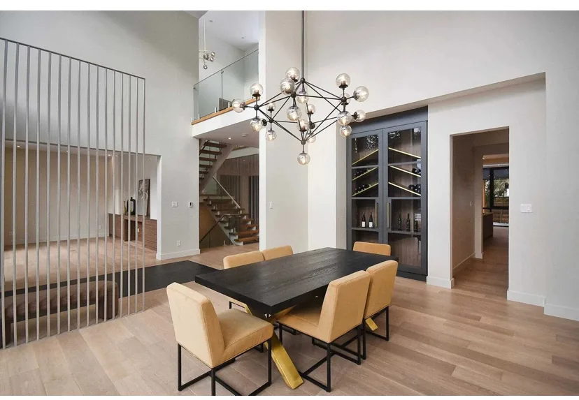 Light hardwood flooring through a modern dining room with open-riser stairs and tall ceilings.
