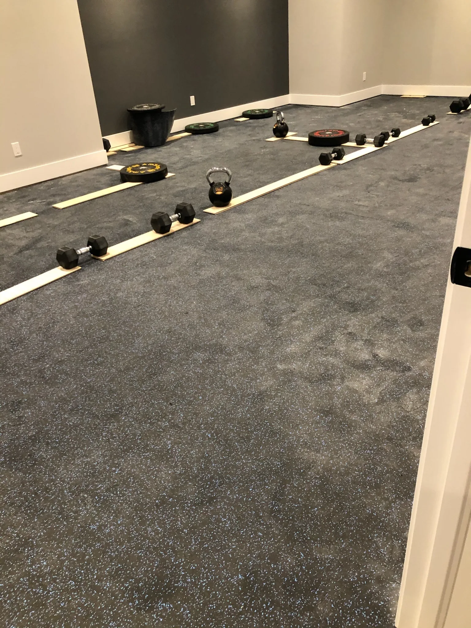 Dark speckled rubber gym flooring in a home fitness room.