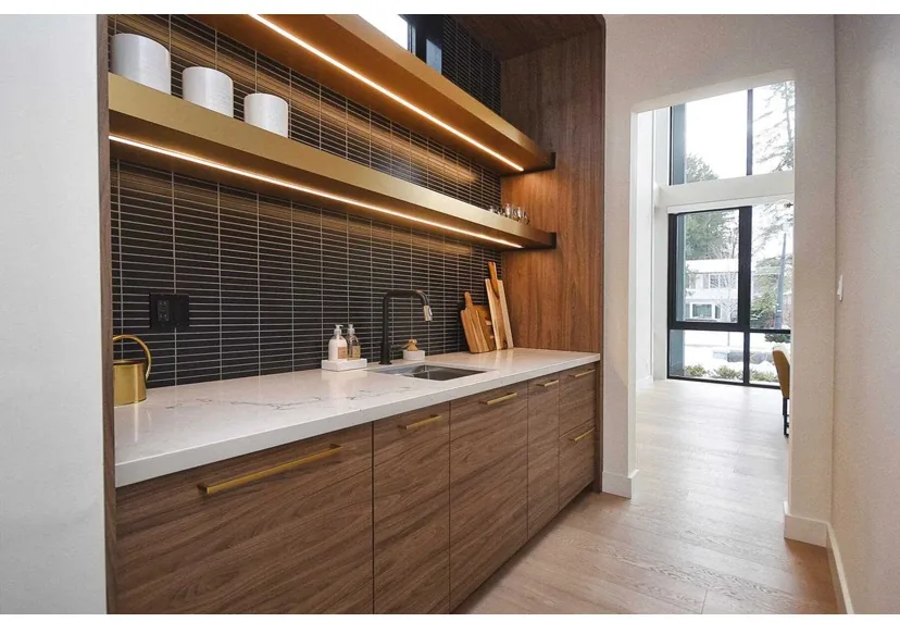 Light flooring beside custom walnut cabinetry with integrated shelf lighting.
